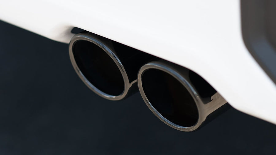 Cat-Back Exhaust Systems by Borla: A close-up of twin black chrome exhaust tips exiting beneath a white rear bumper.