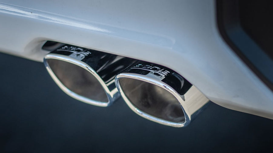 Cat-Back Exhaust Systems by Borla: A close-up of twin polished Borla exhaust tips exiting beneath a white rear bumper.