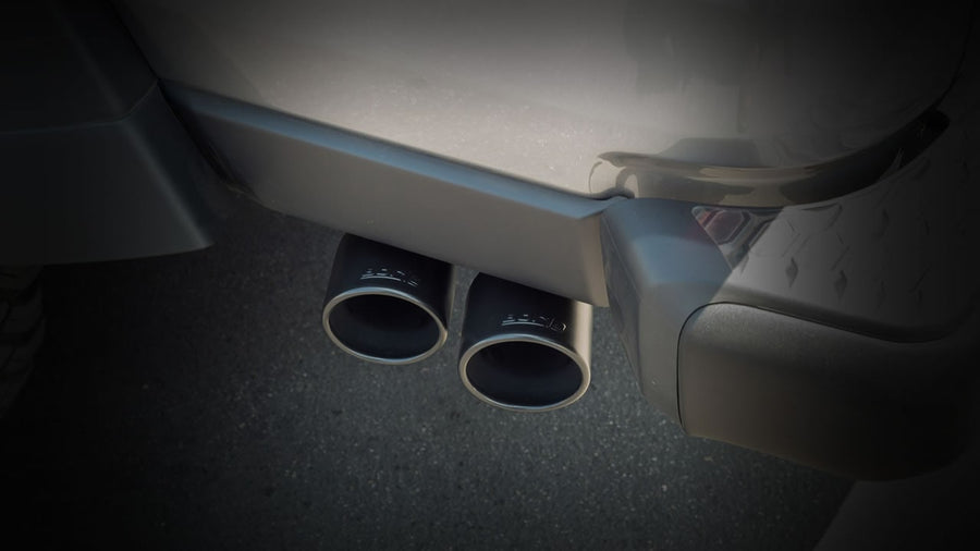 Cat-Back Exhaust Systems by Borla: Dark close view of two black Borla exhaust tips installed under a rear bumper.