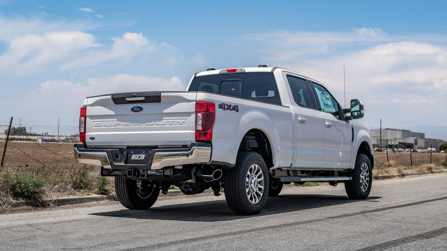 Cat-Back Exhaust Systems by Borla: Rear three-quarter view of a white Ford Super Duty pickup with a Borla exhaust tip ahead of the rear wheel.