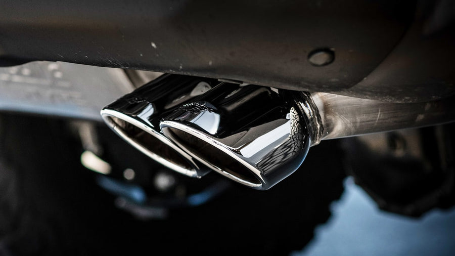 Cat-Back Exhaust Systems by Borla: Close underbody view of two polished round exhaust tips side by side below a dark vehicle.