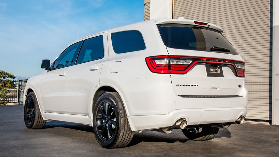 Cat-Back Exhaust Systems by Borla: White Dodge Durango parked by a building, seen from the rear quarter with dual exhaust tips and a Borla plate.