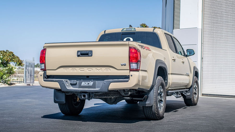Cat-Back Exhaust Systems by Borla: Tan Toyota Tacoma TRD 4x4 seen from the rear quarter with a dark finish side-exit tip ahead of the rear wheel and a Borla plate.