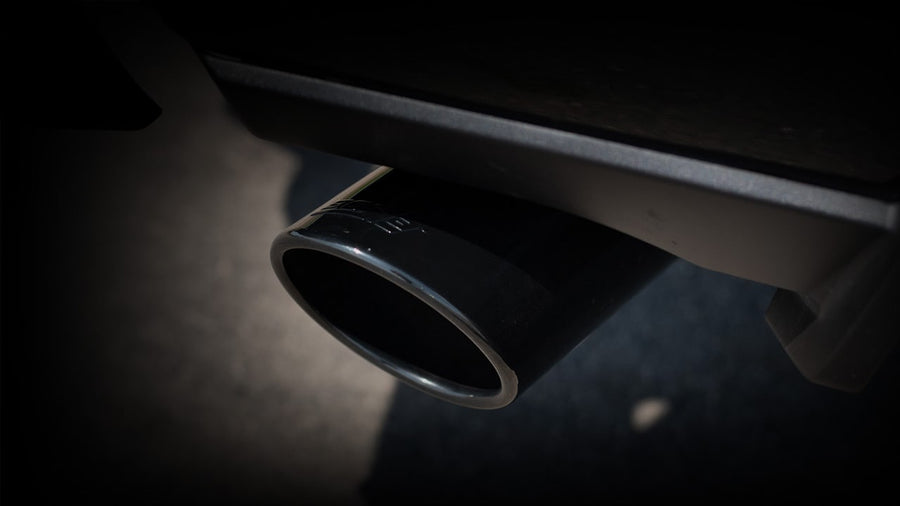 Cat-Back Exhaust Systems by Borla: Close-up of a black chrome Borla tip under a truck bed against a dark background.