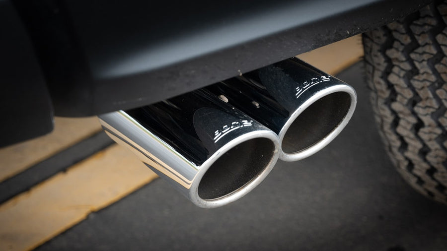 Cat-Back Exhaust Systems by Borla: Close view of dual polished stainless tips with etched Borla lettering exiting ahead of a rear tire.