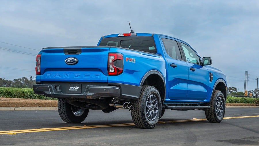 Cat-Back Exhaust Systems by Borla: Blue Ford Ranger FX4 seen from the rear quarter with dual polished exhaust tips exiting ahead of the rear wheel and a Borla plate.