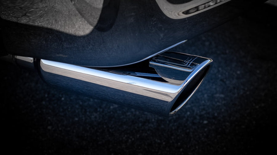 Cat-Back Exhaust Systems by Borla: Close-up of a polished angle-cut exhaust tip beneath a dark vehicle body.