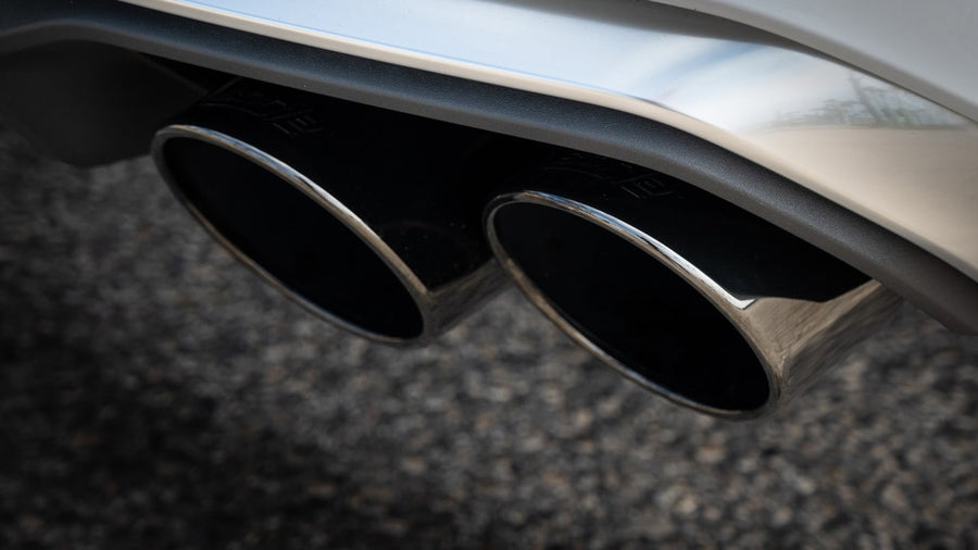 Exhaust Tip Kits by Borla: Twin black chrome exhaust tips installed under the rear diffuser of a white SUV.
