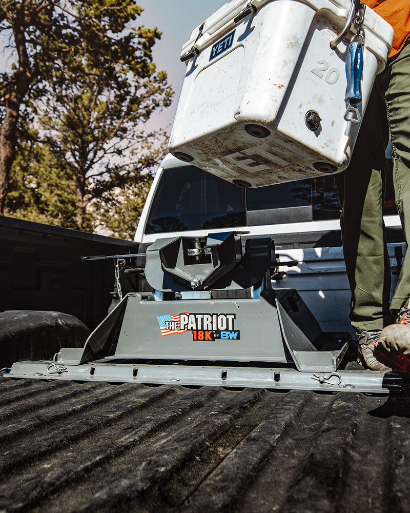 B&W Patriot 18K rail-mounted fifth wheel hitch in a pickup bed while a cooler is loaded
