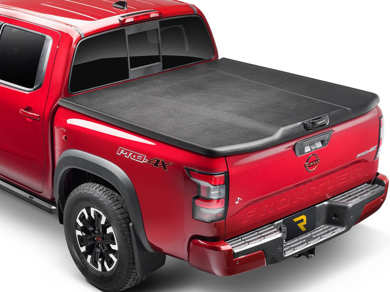 UnderCover Elite one-piece tonneau cover closed and latched on a pickup bed, rear three-quarter studio view, the black textured lid sitting flush on the tailgate cap with no bed floor showing.