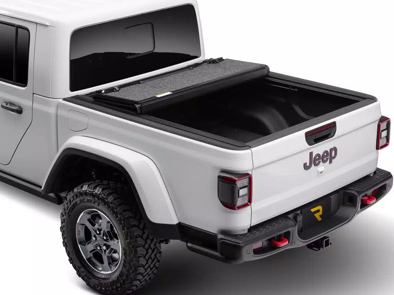 UnderCover Ultra Flex hard folding tonneau cover folded open and stacked at the bulkhead with the bed exposed, rear three-quarter view.