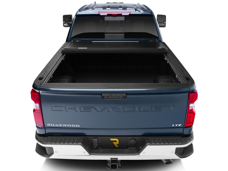 UnderCover Flex hard folding tonneau cover folded open and stacked against the bulkhead with the bed open, straight rear view.