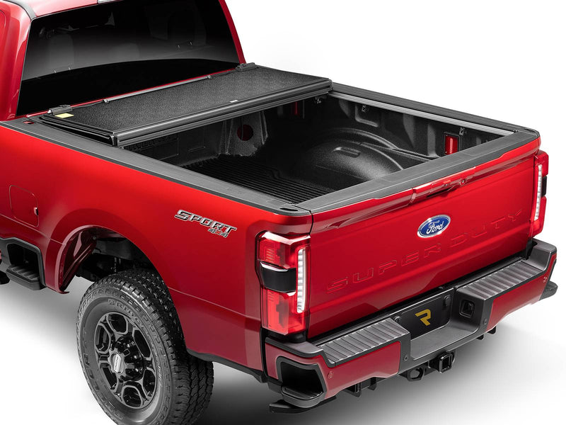 UnderCover Select hard folding tonneau cover folded fully open and stacked flat at the bulkhead with the rear two-thirds of the bed exposed, tailgate closed, rear three-quarter view.