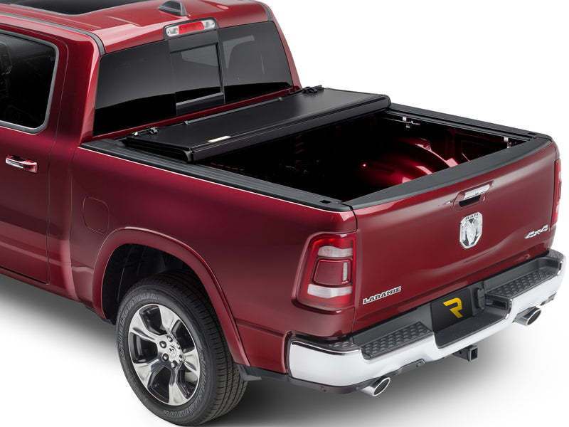 UnderCover ArmorFlex hard folding tonneau cover part-open with two panels folded and stacked against the bulkhead, about half the bed exposed, rear three-quarter view.