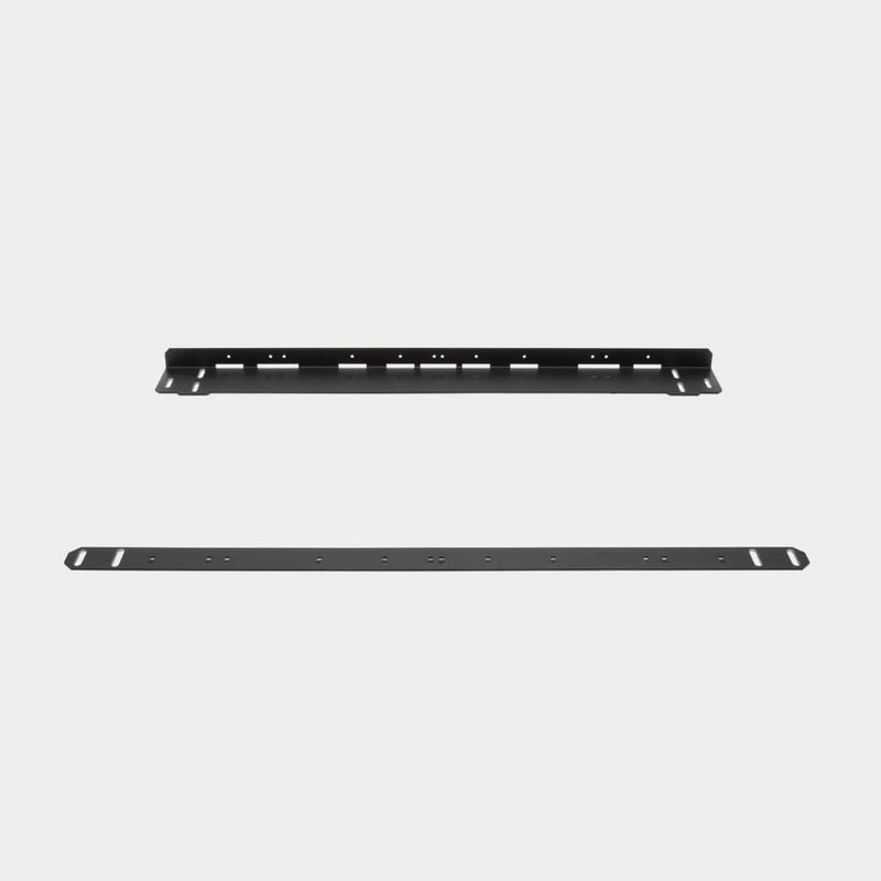 Current DECKED CargoGlide mounting bracket kit shown in studio: one full-length black angled steel rail above one full-length flat perforated strap