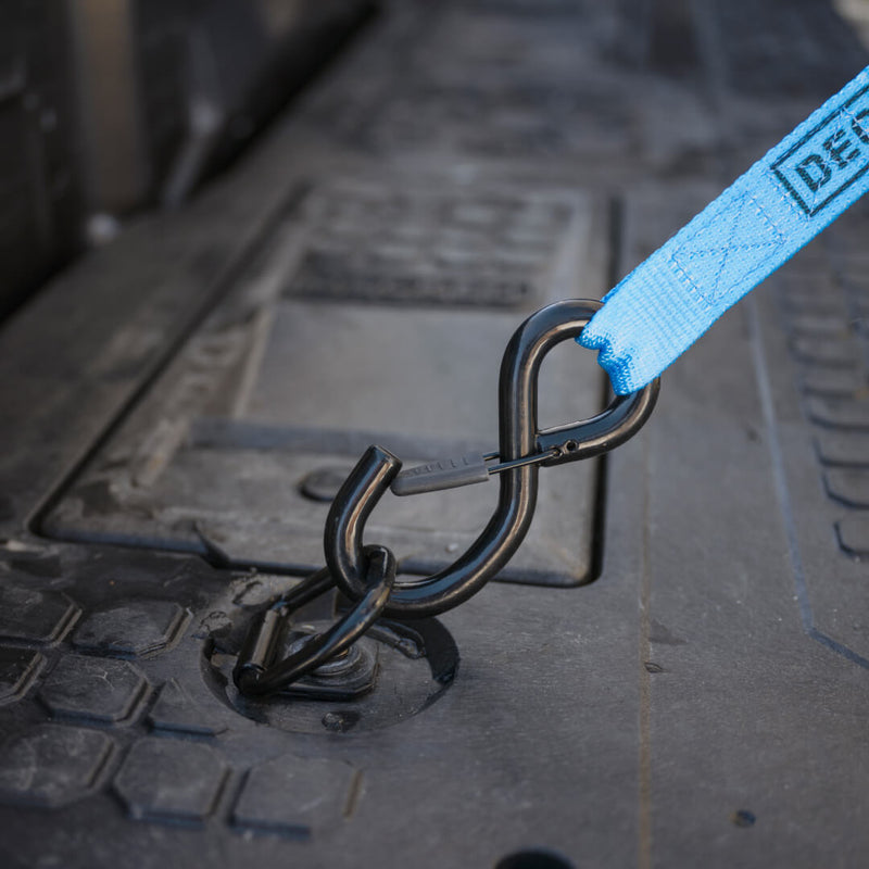 Carabiner clipped through a black DECKED D-ring tie down on the drawer system deck with a DECKED branded strap attached