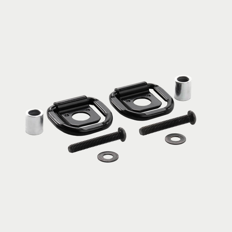 DECKED D-ring tie down set shown in studio: two black folding steel rings on base plates with two aluminum spacers, two bolts and two washers