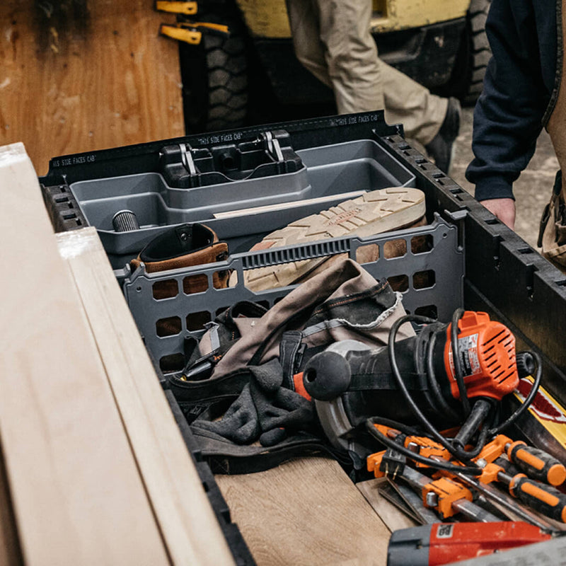 Gray DECKED divider fitted upright inside an open drawer system drawer, separating tools and a work bag from the rest of the load