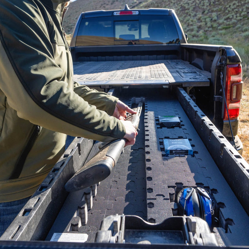 Black DECKED Piecekeeper PuzzleFoam installed the length of an open drawer system drawer, cradling a shotgun with ammunition boxes set into cut pockets