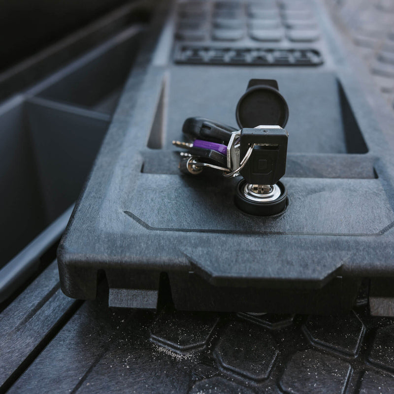 DECKED key with a branded fob turned in the stash bin lock on the corner lid of a DECKED Drawer System deck