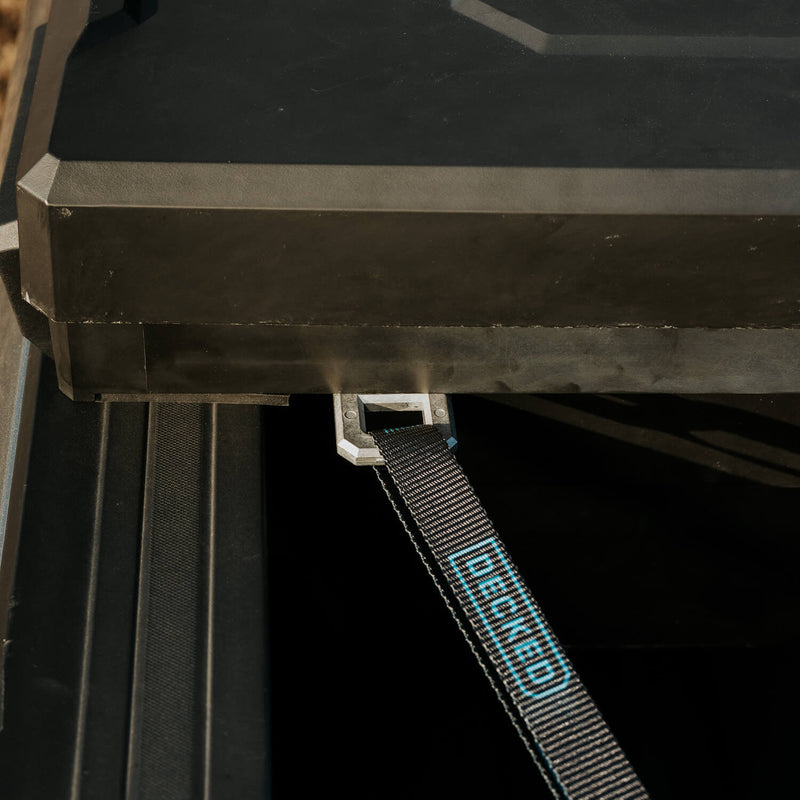 Black DECKED strap threaded through an aluminum D-ring tie down anchor mounted under the lip of a DECKED Tool Box