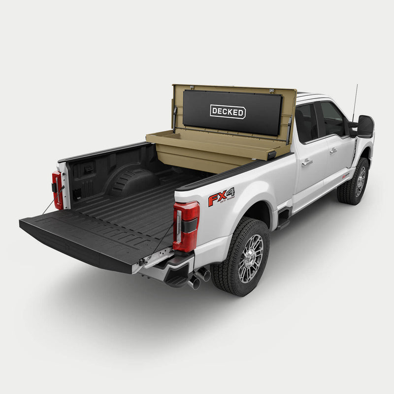 Fender Dirt tan DECKED Tool Box mounted crossbed behind the cab of a white Ford Super Duty, lid open, showing the mounting position and the bed space that stays free behind it