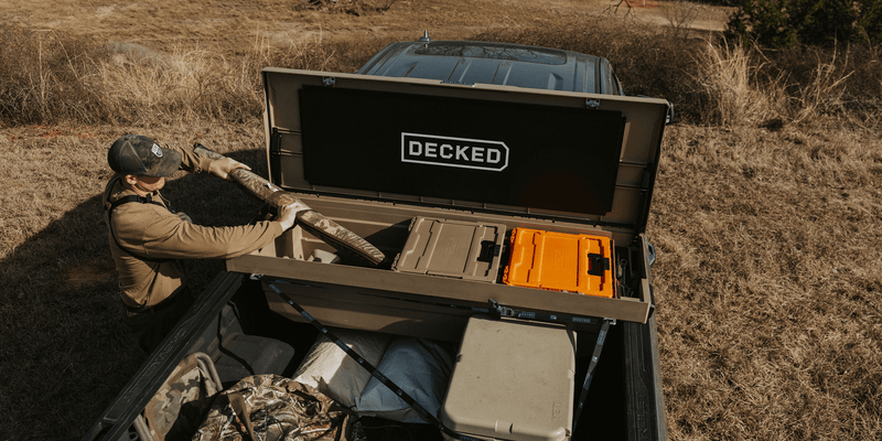 Overhead view of an open Fender Dirt tan DECKED Tool Box in a truck bed with DECKED cases inside and gear strapped down below it