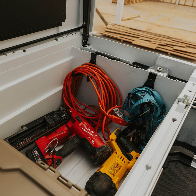 Black DECKED Tool Hooks mounted inside a Tool Box tub holding a coiled orange extension cord and a coiled DECKED strap