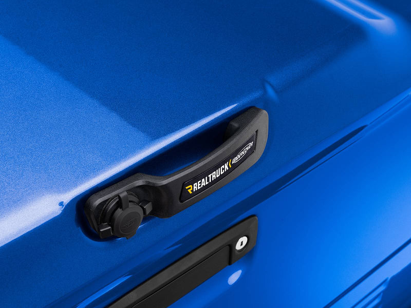 Close-up of the black latch handle and its hinged lock-cylinder cap, set into the painted lid and carrying the UnderCover name.