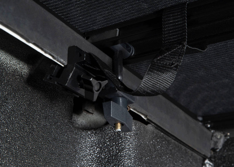 Clamp securing the cover rail under the bed rail, seen from inside the bed