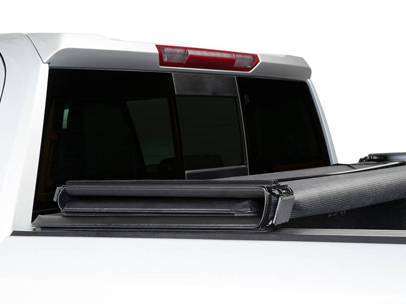 Soft cover fully folded and resting against the cab of a white pickup