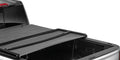 Soft tri-fold tonneau cover with the rear section folded forward over an open pickup bed, rear three-quarter close-up