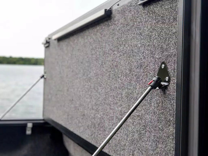 Close-up of a raised Ultra Flex panel's grey underside and its prop-rod pivot bracket, open water out of focus behind.