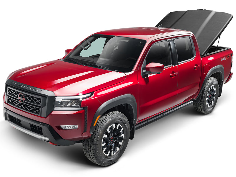UnderCover Elite one-piece tonneau cover raised on its struts, front three-quarter view with the whole truck in frame and the open box behind the cab.