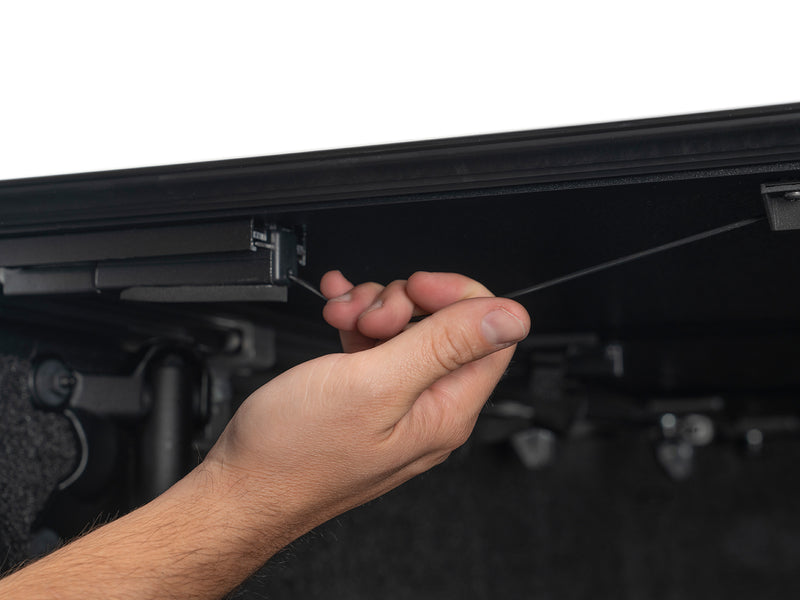 Close-up of the Gator EFX tonneau cover: A hand pulls the release cable under a raised hard cover panel