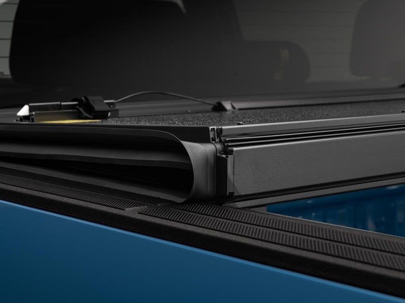 Gator EFX hard folding tonneau cover: Close-up of folded hard tonneau panels stacked on the rail of a blue truck bed, showing the hinge and seal
