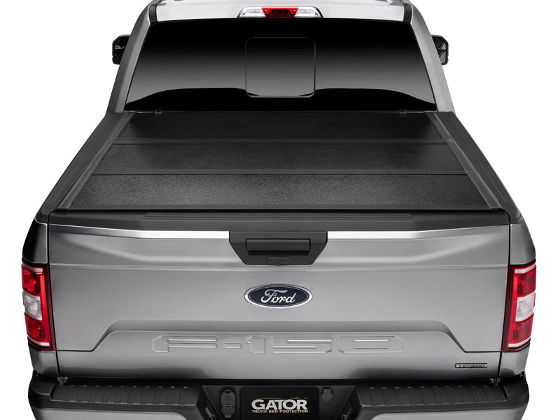 Gator EFX hard folding tonneau cover: Rear view of a silver Ford F-150 with the black hard tri-fold cover closed flat