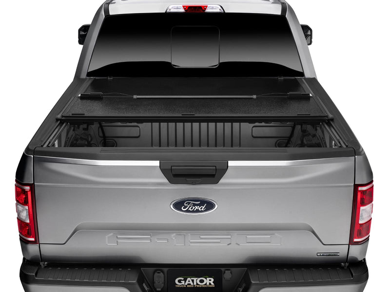 Gator EFX hard folding tonneau cover: Rear view of a silver Ford F-150 with the hard tri-fold cover folded part way toward the cab