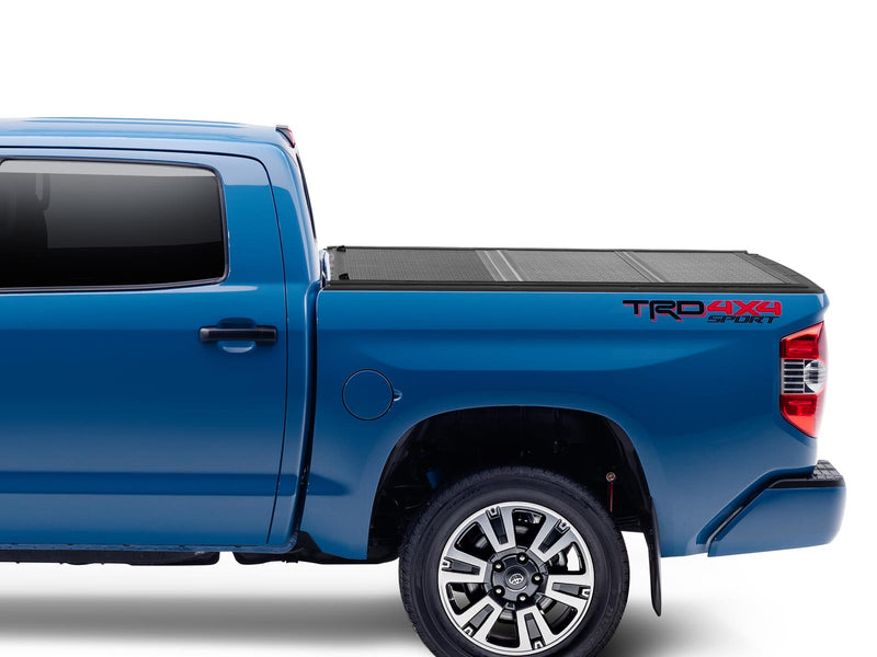 Gator EFX hard folding tonneau cover: Side profile of a blue Toyota Tundra TRD 4x4 with a black hard folding tonneau cover closed flush over the bed