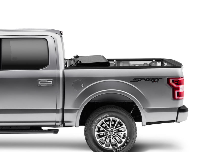 Gator EFX hard folding tonneau cover: Side view of a silver Ford F-150 with the hard tri-fold cover fully folded against the cab and the bed open
