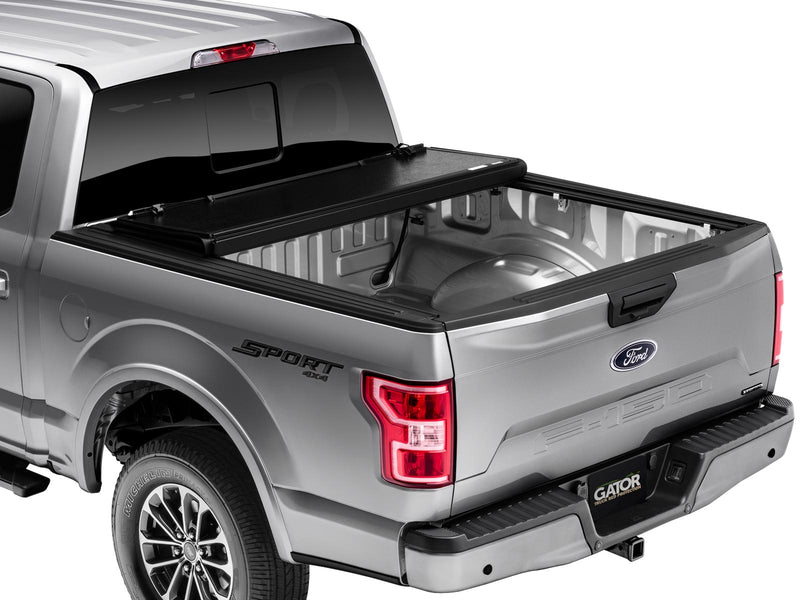 Gator EFX hard folding tonneau cover: Silver Ford F-150 from the rear three-quarter with the hard tri-fold cover folded against the cab