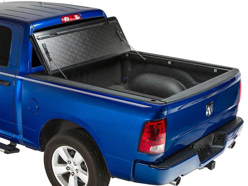 Gator FX hard folding tonneau cover: all panels folded and propped upright against the cab of a blue Ram pickup