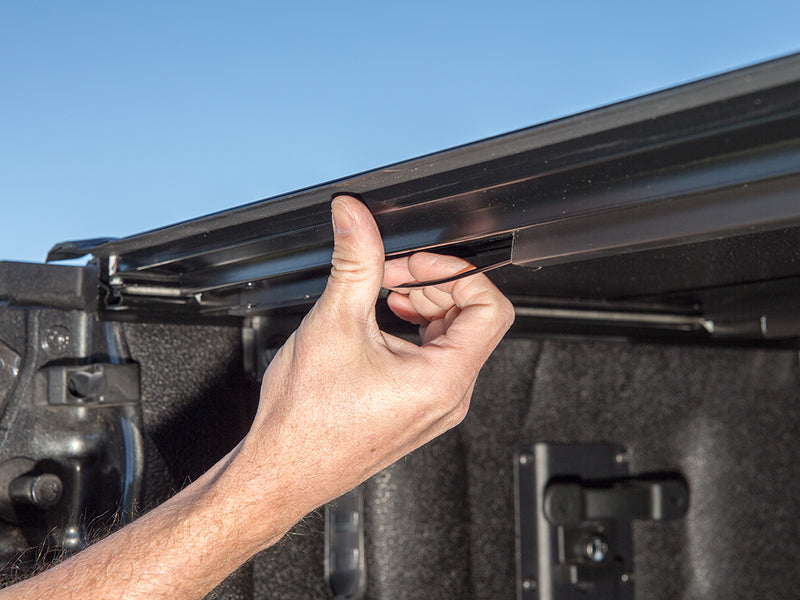 Gator FX hard folding tonneau cover: hand lifting the rear panel edge at the tailgate