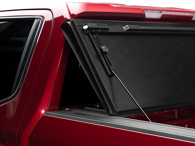 Gator FX hard folding tonneau cover: folded panels propped upright against the cab of a red pickup