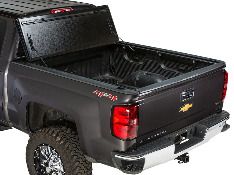Gator FX hard folding tonneau cover: all panels folded and propped upright against the cab of a dark gray pickup
