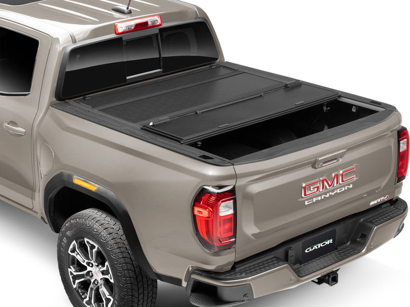 Gator FX tonneau cover (partial) on a GMC Canyon: rear three-quarter view of a tan GMC Canyon with the rear section of a black hard folding cover folded forward