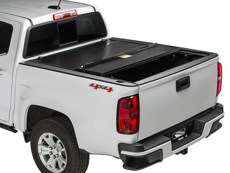 Gator FX hard folding tonneau cover: rear panel folded forward on a white Chevrolet midsize pickup