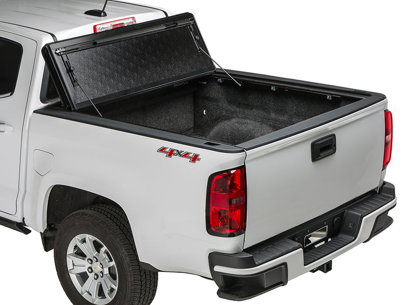 Gator FX hard folding tonneau cover: all panels folded and propped upright against the cab of a white Chevrolet midsize pickup
