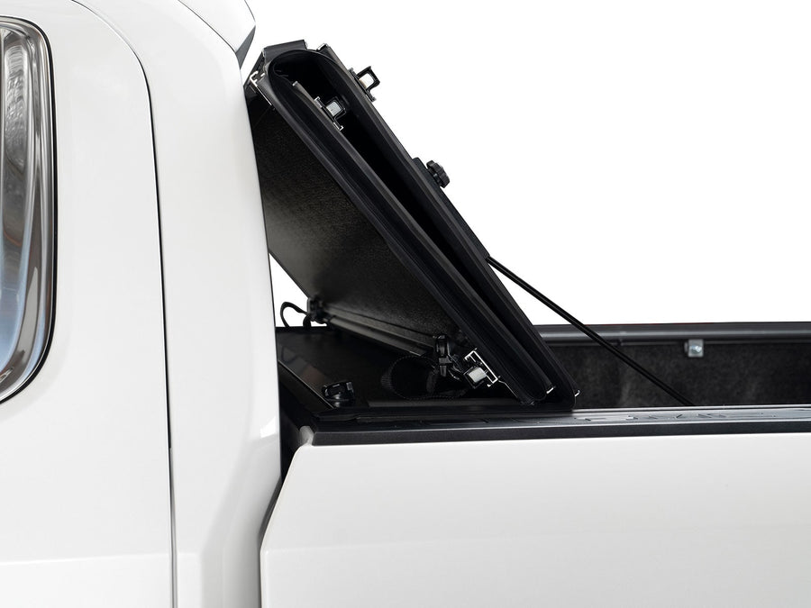 Gator FX Hard Folding tonneau cover: Side view of a hard folding tonneau cover raised upright behind the cab of a white truck.