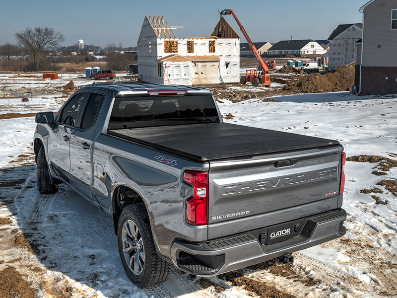 Gator SFX soft tri-fold tonneau cover: closed on a silver Chevrolet pickup parked in snow